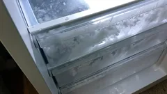 Mraznička se silnou vrstvou námrazy na zásuvkách, potřeba odmrazit lednici.